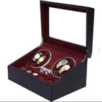 Black jewelry watch winder box with red interior containing luxury watches and jewelry on a white background