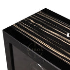 Close-up of a black and white striped surface with a clear glass panel of a luxury watch winder