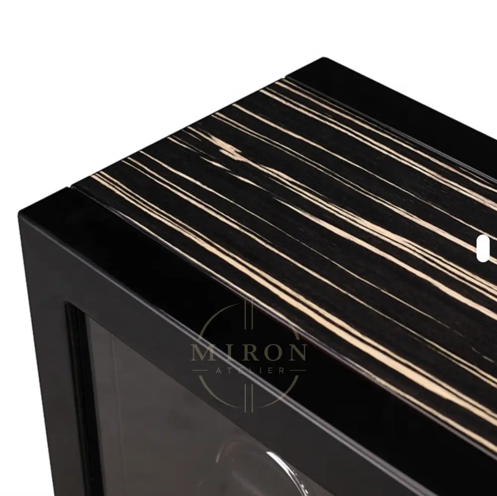 Close-up of a black and white striped surface with a clear glass panel of a luxury watch winder