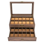 A wooden watch box with a glass lid, shown open to reveal two tiers of watch slots lined with tan velvet. The box has a dark brown wood grain finish with brass-tone metal hardware.