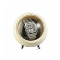 Silver Cartier watch in a round, beige auto watch winder on a white background