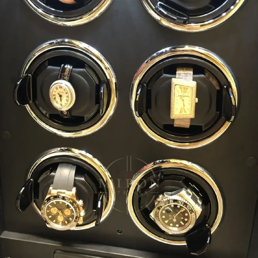Four watches in a black and gold watch winder
