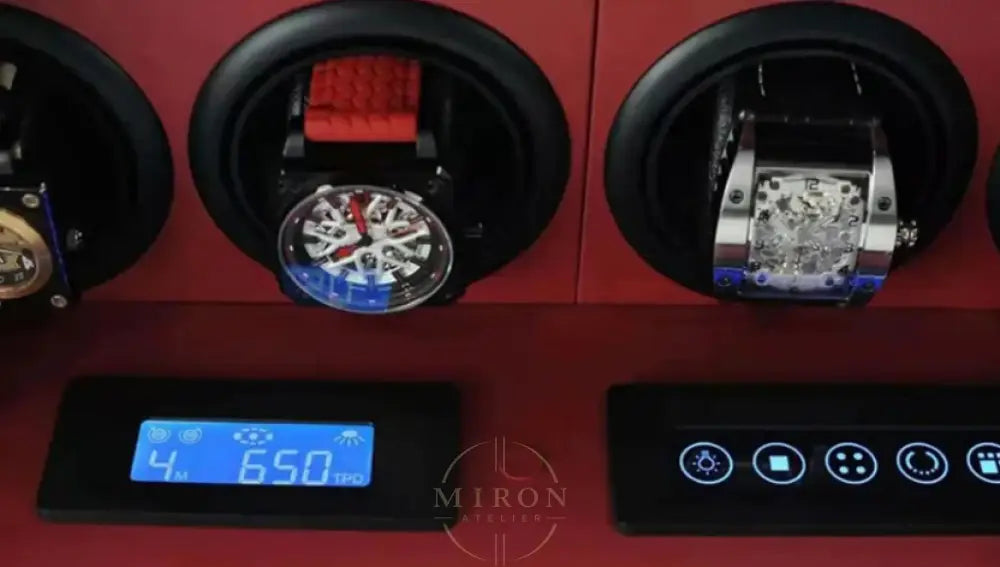 Watch winder with two watches inside and digital display on a red background