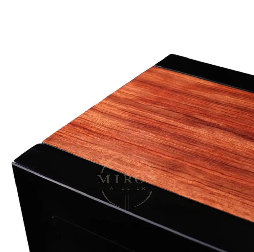 Wooden surface of watch winder with black trim on a white background