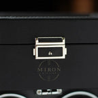 Close-up of a black leather suitcase with a gold clasp.