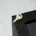 Black leather case with a key and keychain tool on a light gray background