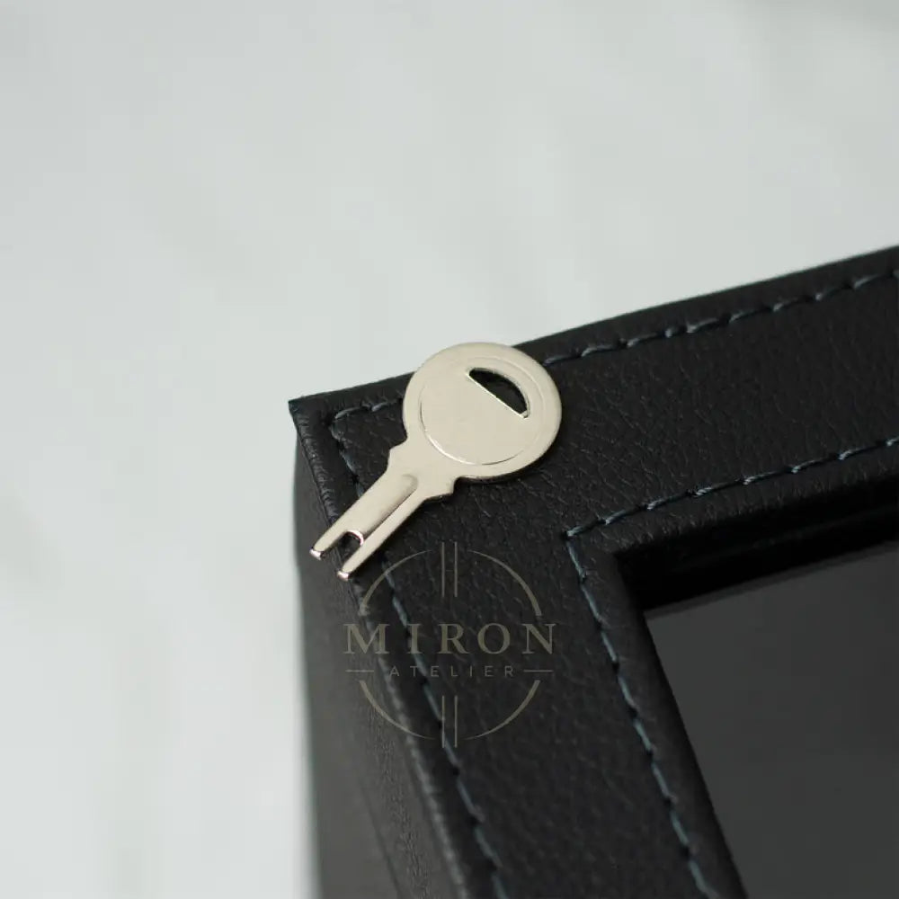 Black leather case with a key and keychain tool on a light gray background