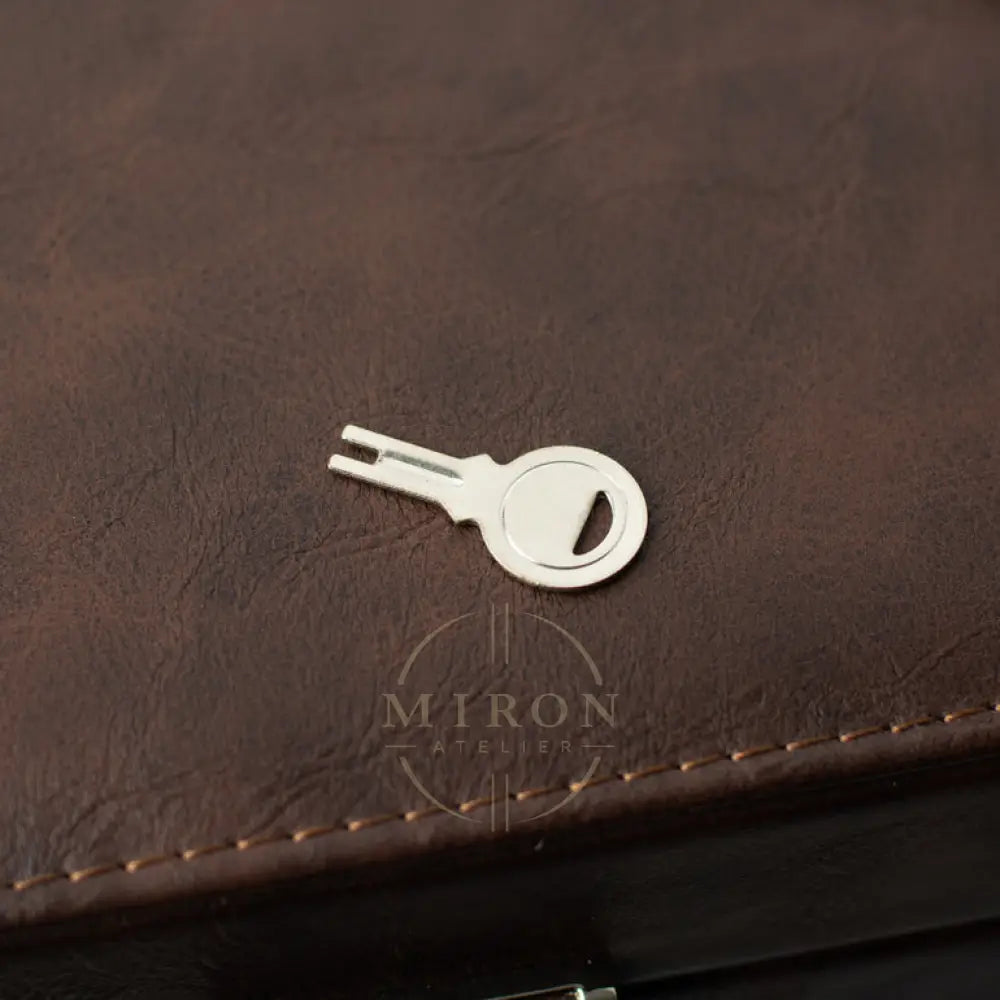 Silver key-shaped bottle opener on a brown leather surface
