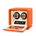 Orange watch winder with two watches inside on a white background