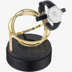 Luxury watch stand with gold loops and a black watch winder on a white background