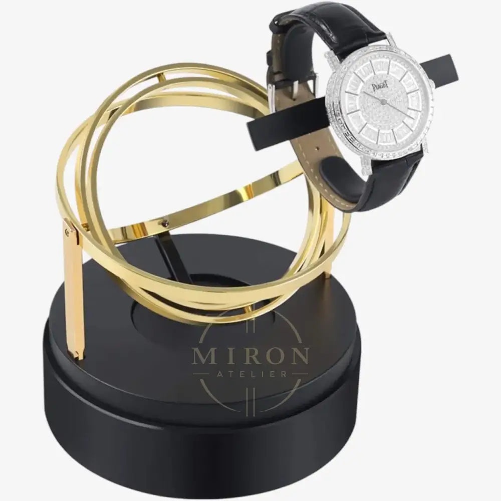 Luxury watch stand with gold loops and a black watch winder on a white background