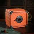 Orange quilted safe watch winder box with a black handle on a dark wooden surface.