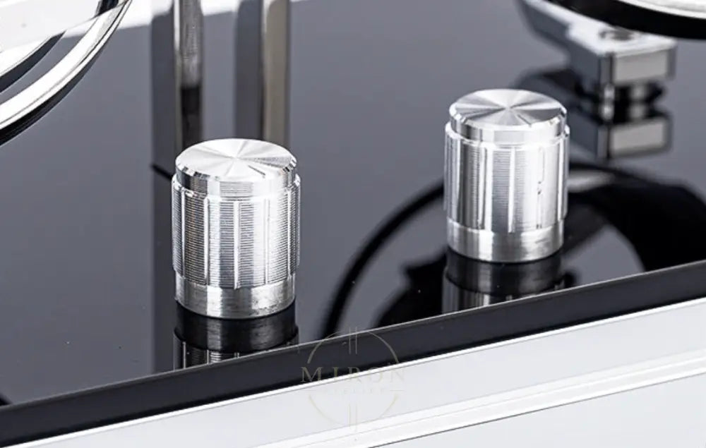 Close-up of metallic knobs on a reflective surface of an automatic watch winder