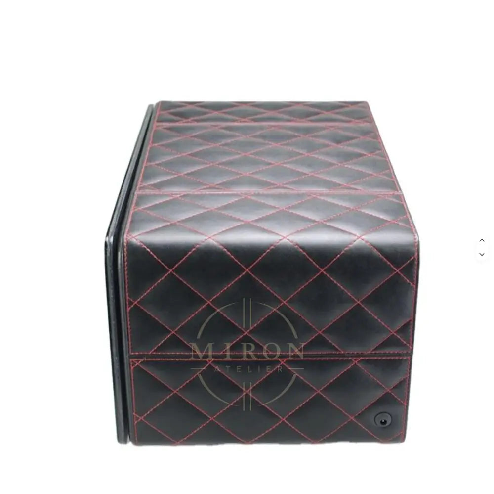 Black quilted leather watch winder side mat with red stitching on a white background