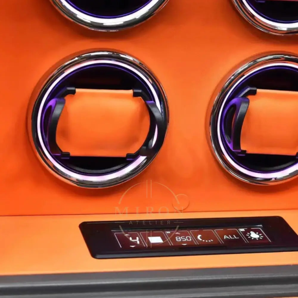 Close-up of an orange watch winder interior with control knobs and digital display.