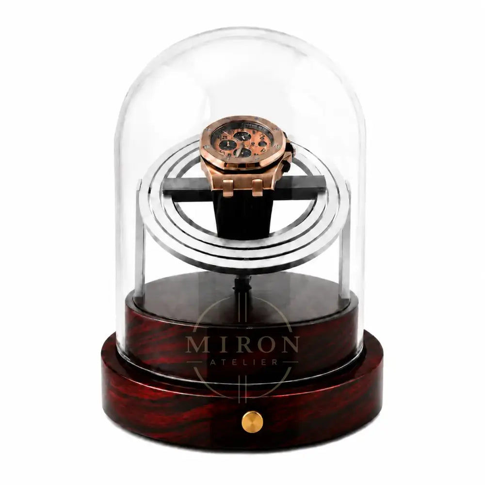 Rose gold watch inside a clear glass dome on a wooden base with a white background. Watch Winder Wood Finition