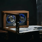 Wooden watch winder opened with two watches inside on a dark background