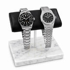 Two silver luxury watches Tudor and Audemars Piguet on a marble watch stand with a white background